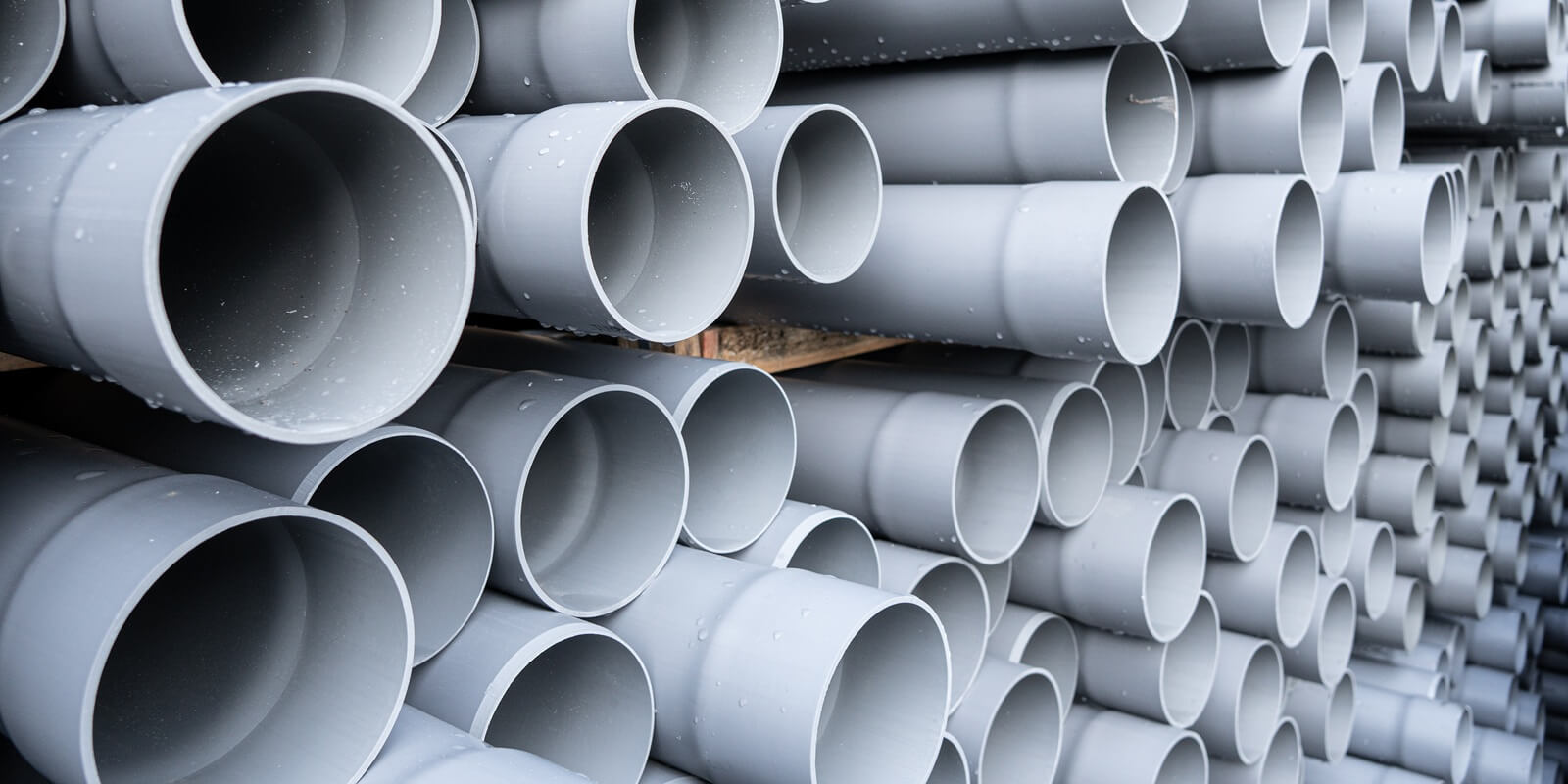 gray PVC tubes plastic pipes stacked in rows
