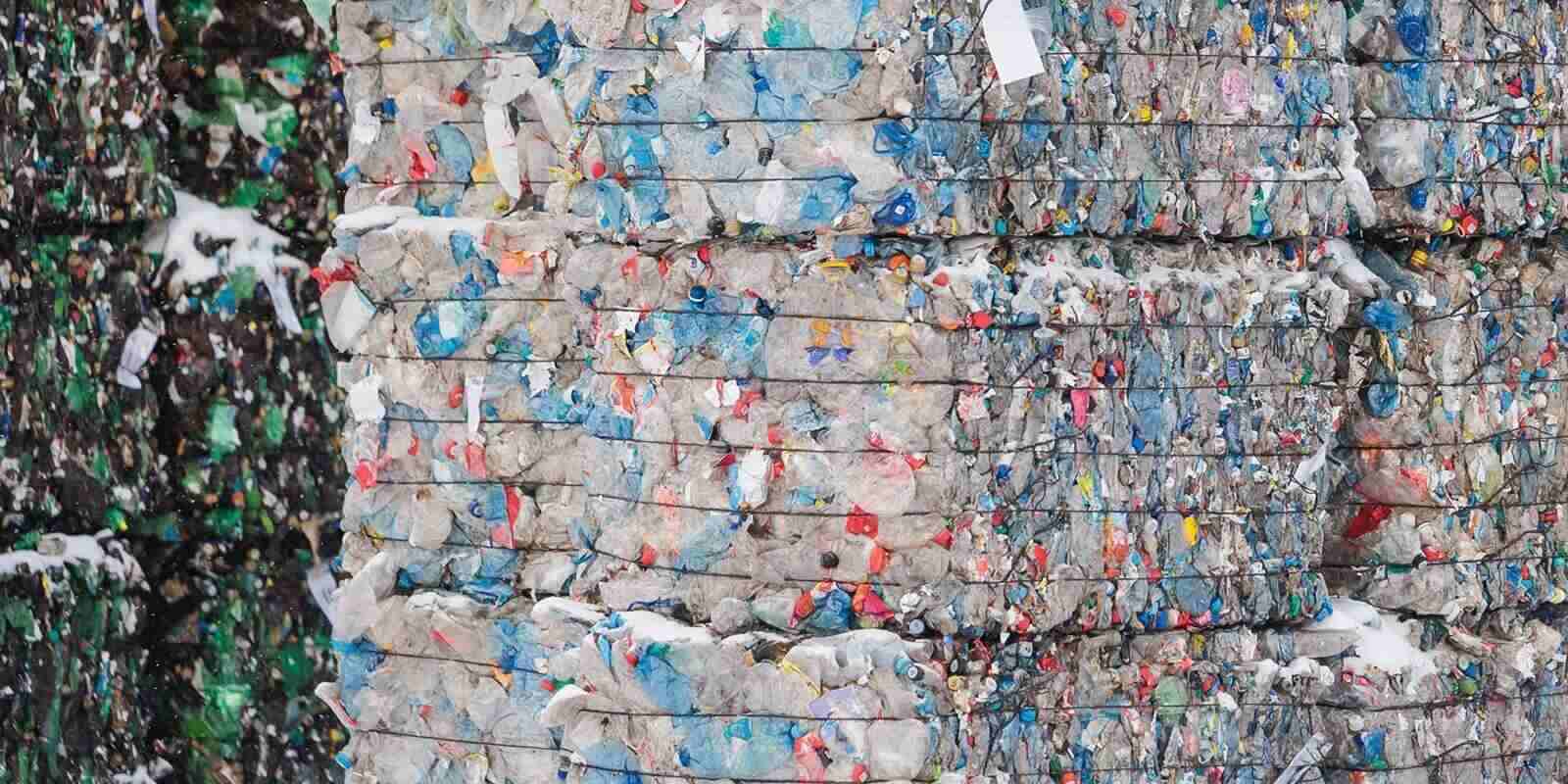 compressed blocks of recycled plastic waste in large stacks on garbage recycling plant