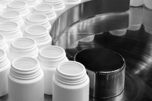 filling and packaging machine at pharmaceutical factory fills white plastic jars with tablets or ampoules containing dietary supplements