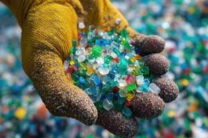 gloved hand cradles a vibrant collection of recycled plastic pellets