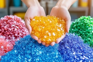 hands holding colorful plastic granules against a vibrant pile
