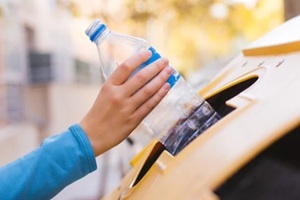 hand putting plastic bottle in a recycle bin