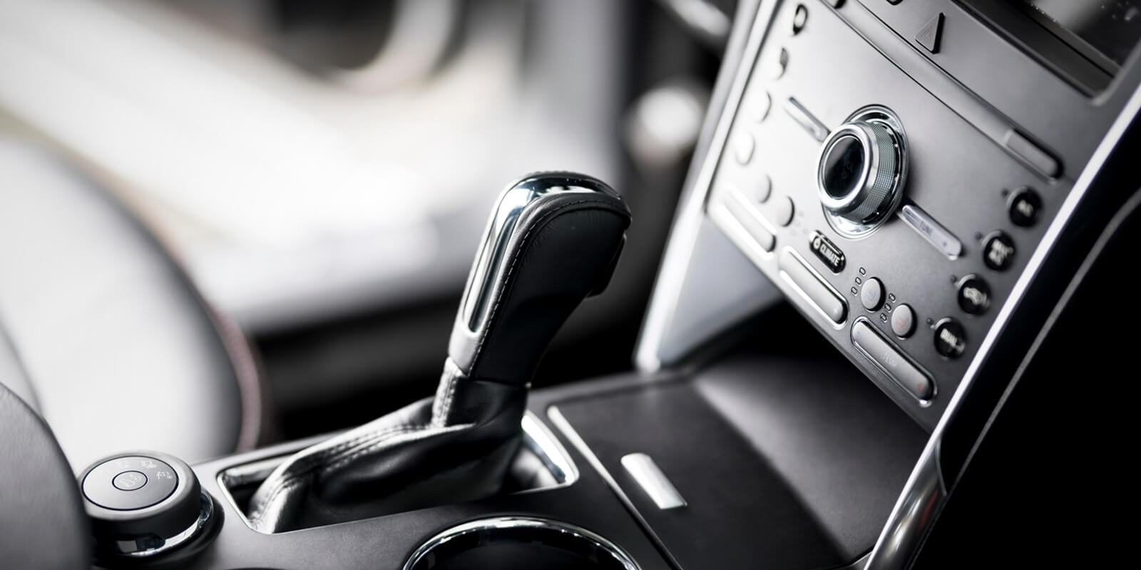 car inside, automatic transmission close up, cup holders and armrest, black leather seats