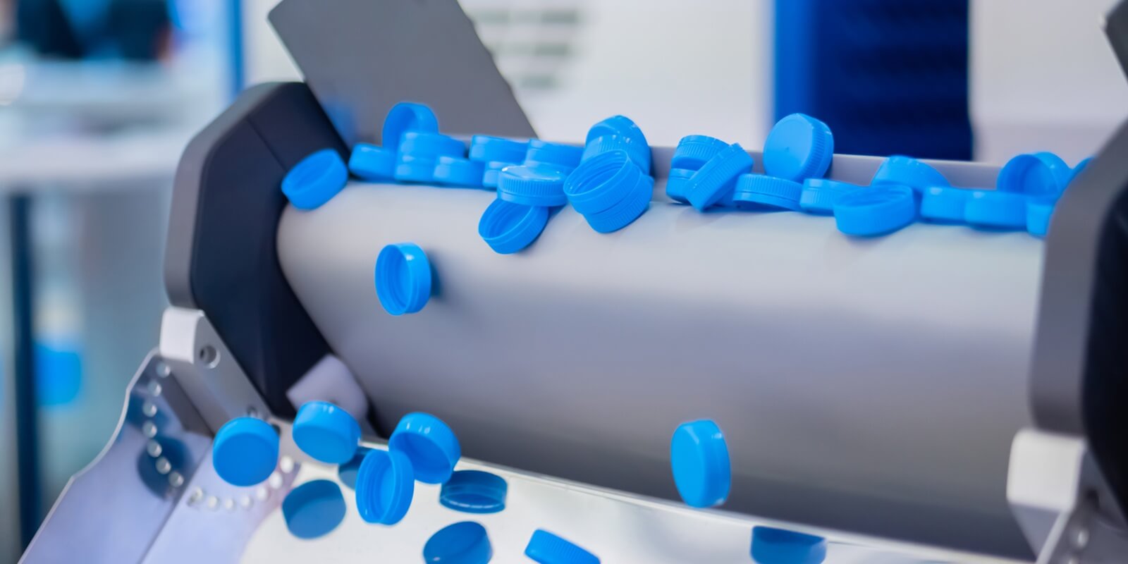 many blue plastic bottle caps falling from conveyor belt at factory, exhibition