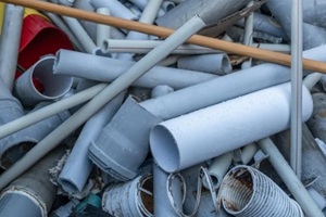 pile of discarded gray plumbing tubes and plastic pipes