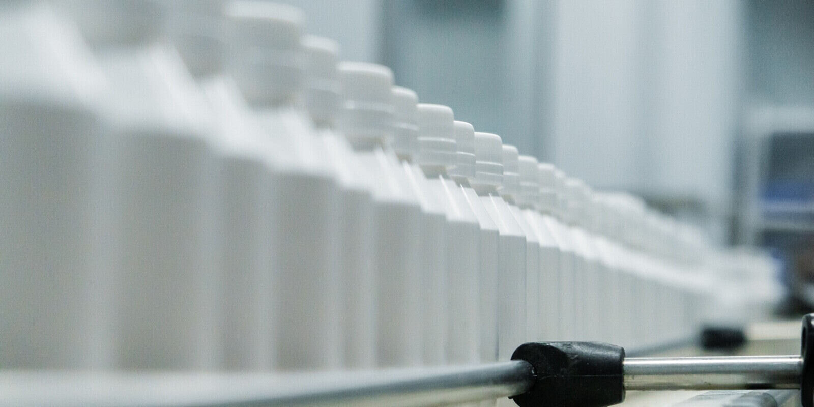 white plastic medicine bottles on conveyor belt in pharmaceutical factory production line